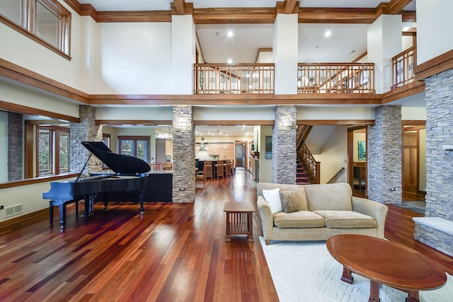 living room with decorative columns, a high ceiling, stairway, wood-type flooring, and beam ceiling