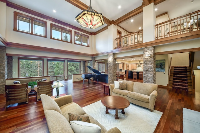 living area featuring ornate columns, a towering ceiling, stairway, wood finished floors, and recessed lighting