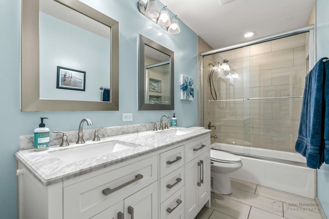 full bathroom featuring a sink, toilet, double vanity, and shower / bath combination with glass door