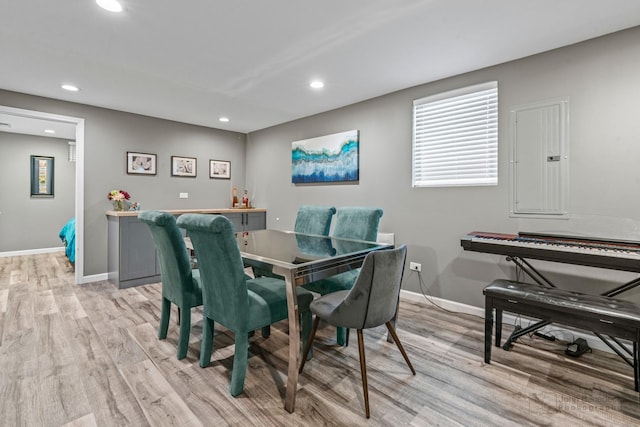 dining room with baseboards, light wood finished floors, recessed lighting, and electric panel