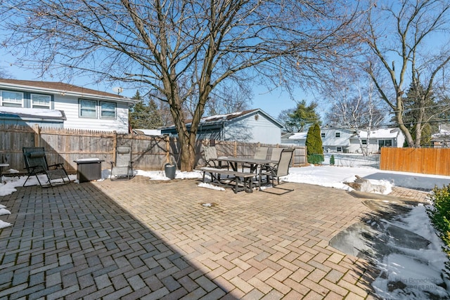 snow covered patio featuring a fenced backyard and outdoor dining space