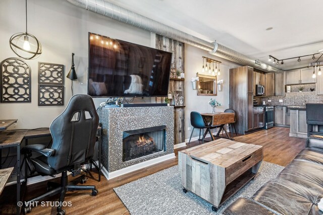 1200 W Monroe St Unit 605, Chicago, IL 60607 - living room with track lighting, wood finished floors, a tiled fireplace, and baseboards