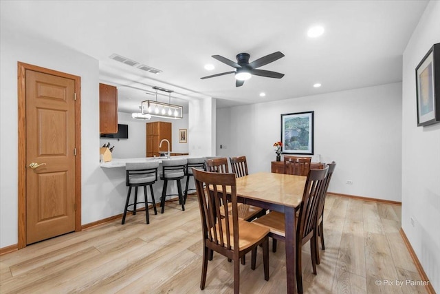 dining room with baseboards, ceiling fan, light wood finished floors, and visible vents