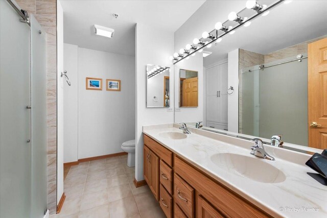 full bath with double vanity, a sink, a stall shower, and toilet