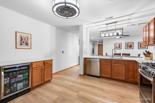 kitchen featuring visible vents, brown cabinetry, wine cooler, a sink, and stainless steel appliances
