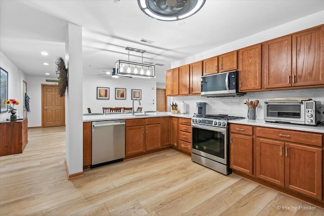 kitchen featuring a toaster, appliances with stainless steel finishes, and brown cabinets