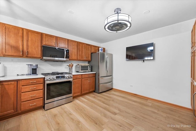 kitchen featuring light wood-style floors, brown cabinetry, light countertops, and stainless steel appliances