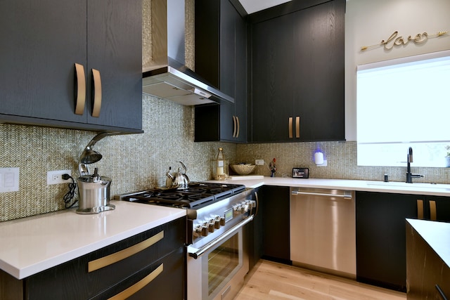 262 N Addison Ave, Elmhurst, IL 60126 - kitchen with stainless steel appliances, wall chimney exhaust hood, dark cabinetry, light wood-style flooring, and light countertops