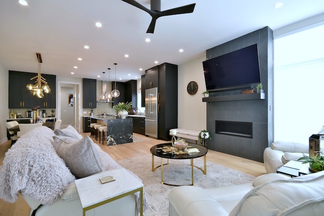 262 N Addison Ave, Elmhurst, IL 60126 - living room with a chandelier, a tiled fireplace, light wood-style floors, a ceiling fan, and recessed lighting