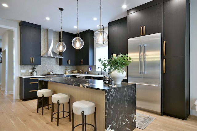 262 N Addison Ave, Elmhurst, IL 60126 - kitchen featuring stainless steel appliances, wall chimney range hood, a breakfast bar, decorative backsplash, and light wood-type flooring
