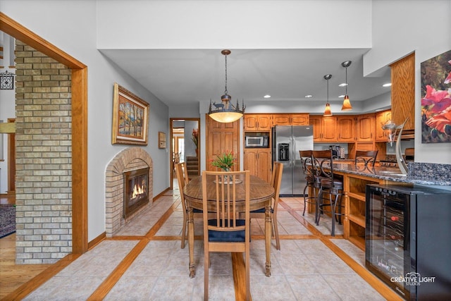 dining space featuring wine cooler, inlaid floor details, a brick fireplace, light tile patterned flooring, and recessed lighting