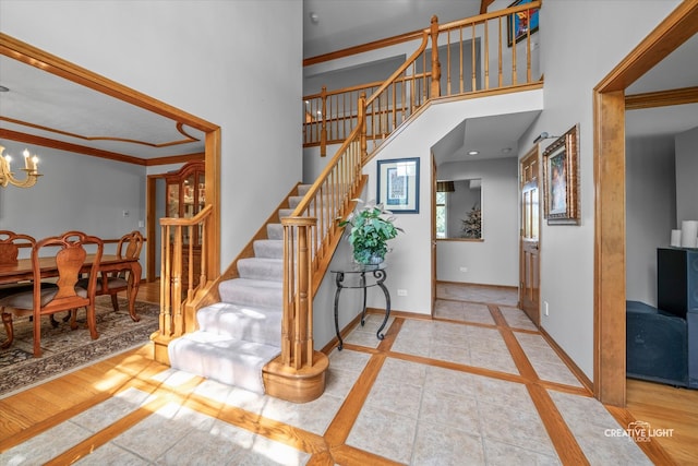 entrance foyer with inlaid floor details, stairway, a chandelier, baseboards, and a high ceiling