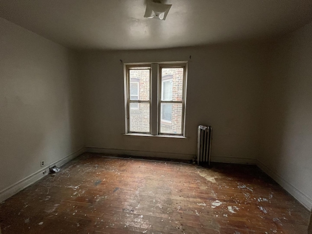 empty room with radiator heating unit and baseboards