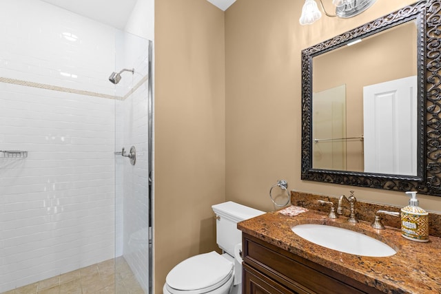 bathroom featuring toilet, tiled shower, and vanity