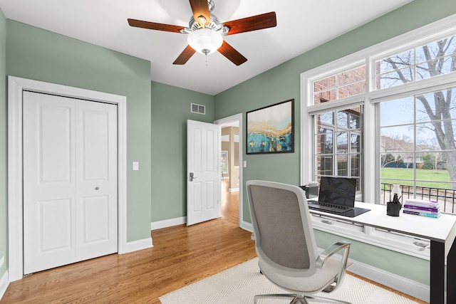 office area with light wood finished floors, baseboards, a ceiling fan, and visible vents
