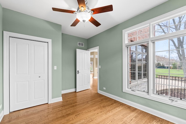 unfurnished bedroom featuring a closet, baseboards, light wood-style flooring, a ceiling fan, and visible vents
