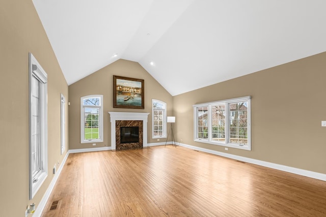 unfurnished living room featuring baseboards, vaulted ceiling, a fireplace, light wood-style floors, and visible vents