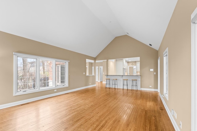 unfurnished living room featuring light wood-style floors, high vaulted ceiling, baseboards, and visible vents