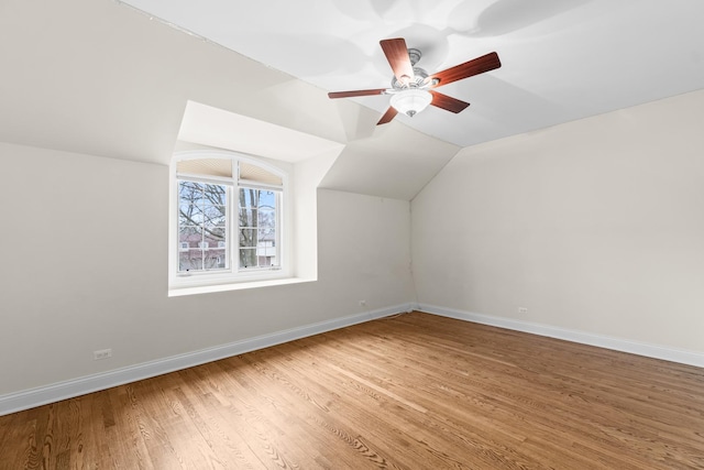 bonus room featuring light wood-style floors, baseboards, a ceiling fan, and vaulted ceiling