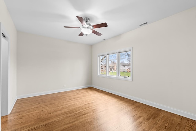 empty room with light wood finished floors, baseboards, a ceiling fan, and visible vents