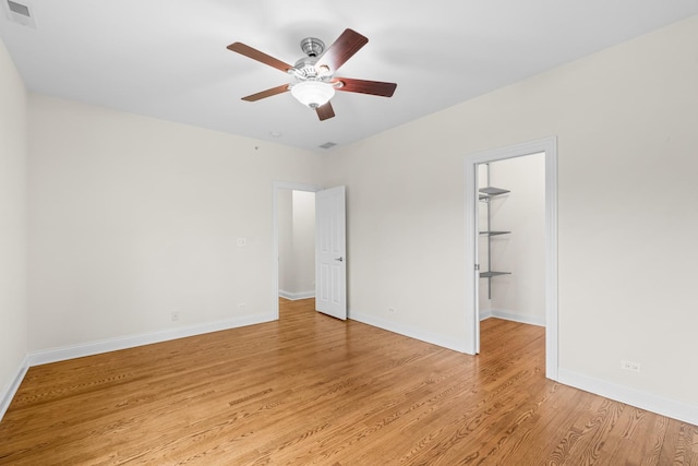 unfurnished bedroom featuring baseboards, a closet, a spacious closet, light wood-style flooring, and visible vents