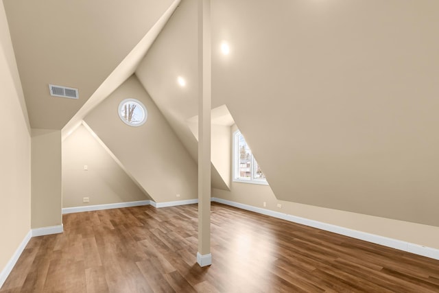 additional living space featuring visible vents, baseboards, vaulted ceiling, and wood finished floors