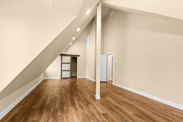 bonus room with wood finished floors, recessed lighting, baseboards, and a barn door