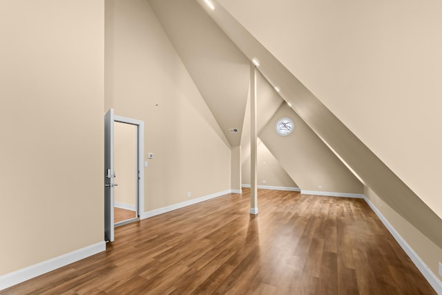 additional living space with wood finished floors, visible vents, baseboards, and lofted ceiling