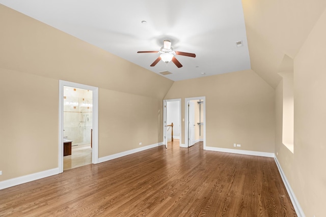 interior space featuring visible vents, baseboards, vaulted ceiling, and wood finished floors