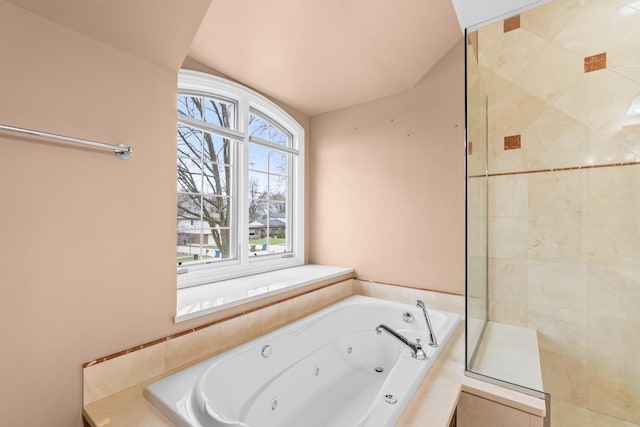 full bath featuring a whirlpool tub, a wealth of natural light, and tiled shower