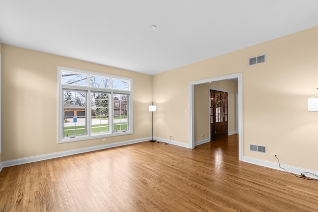 spare room with visible vents, baseboards, and wood finished floors