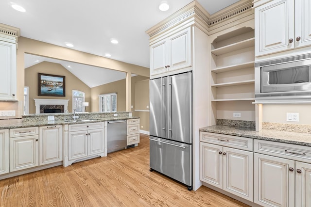 kitchen with open shelves, a sink, appliances with stainless steel finishes, light wood finished floors, and vaulted ceiling
