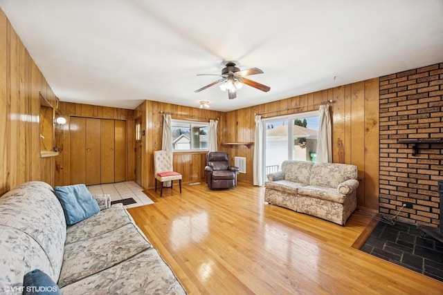 living area featuring wood walls, visible vents, a ceiling fan, and wood finished floors