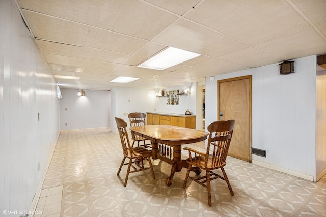 dining area featuring baseboards, a drop ceiling, visible vents, and light floors
