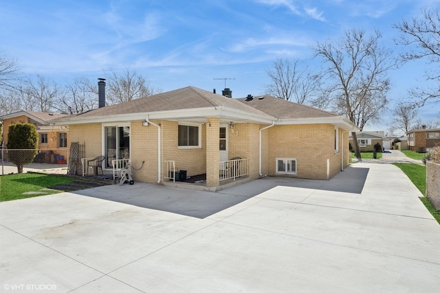 rear view of house with brick siding, fence, and a patio