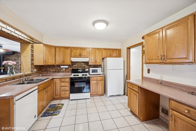kitchen featuring tasteful backsplash, light tile patterned floors, a sink, white appliances, and under cabinet range hood