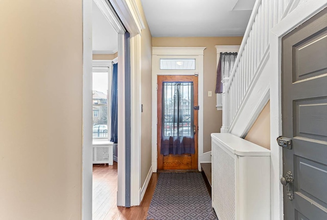 foyer entrance featuring stairway, baseboards, and wood finished floors