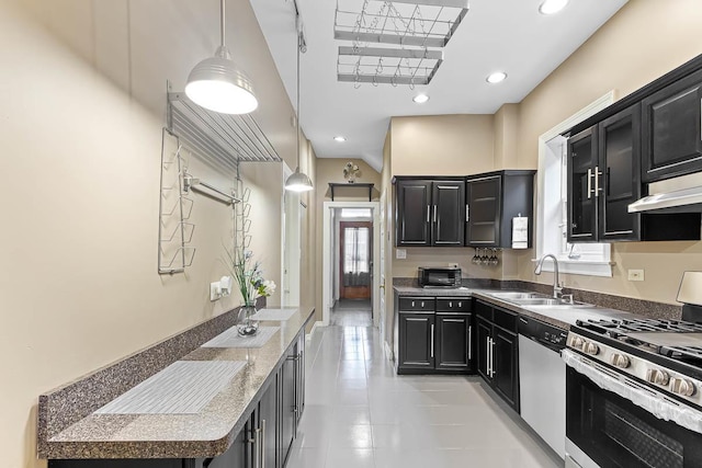 kitchen with hanging light fixtures, a sink, appliances with stainless steel finishes, dark cabinetry, and under cabinet range hood