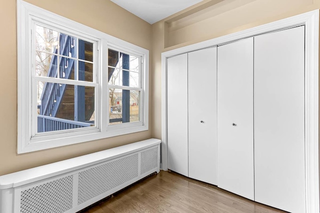 unfurnished bedroom with a closet, radiator, and wood finished floors