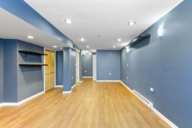 finished basement featuring a baseboard radiator, recessed lighting, baseboards, and light wood-type flooring