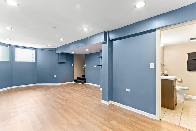 below grade area featuring recessed lighting, stairway, light wood-style floors, and baseboards
