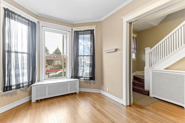 unfurnished room featuring baseboards, ornamental molding, stairway, wood-type flooring, and radiator heating unit