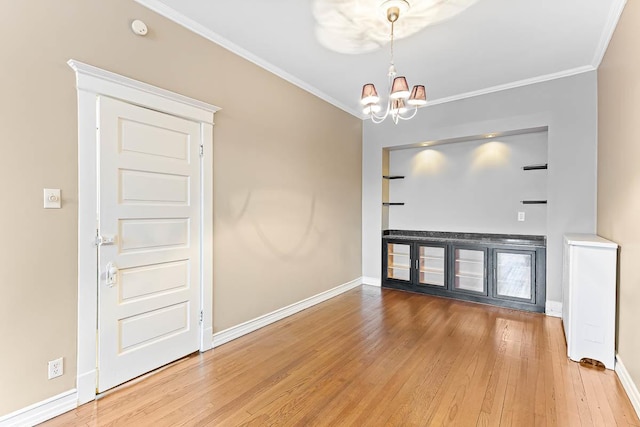 unfurnished living room featuring a notable chandelier, hardwood / wood-style flooring, and crown molding