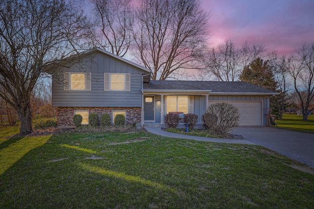 split level home with a garage, concrete driveway, and a front lawn