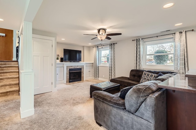 living room with ceiling fan, a fireplace, recessed lighting, stairs, and light carpet