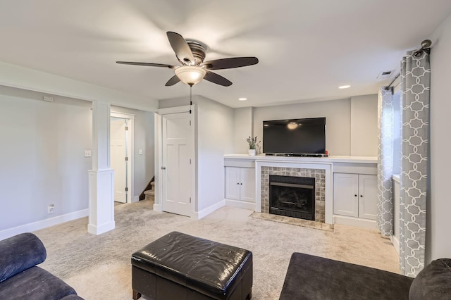 carpeted living room featuring ceiling fan, baseboards, visible vents, and stairs