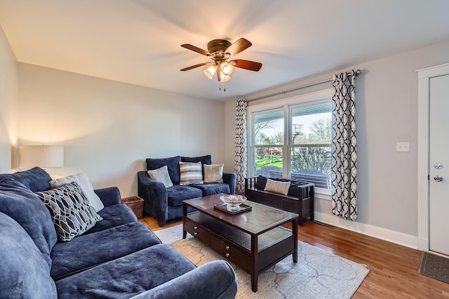 living area with baseboards, a ceiling fan, and wood finished floors