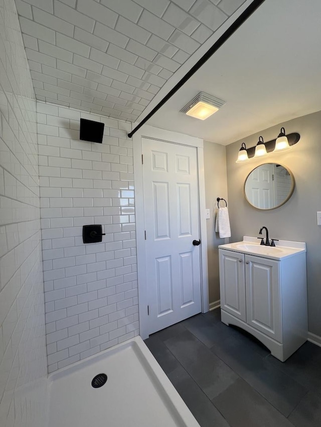 bathroom featuring vanity, baseboards, and a tile shower