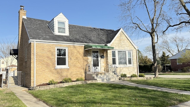 new england style home with a chimney, stone siding, a front yard, brick siding, and a shingled roof