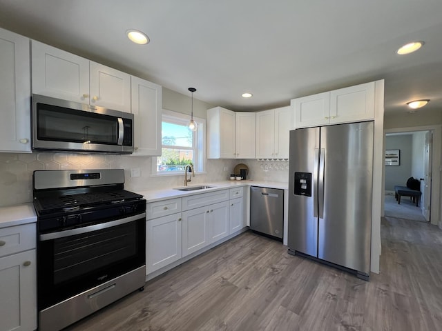 kitchen with light countertops, wood finished floors, a sink, and stainless steel appliances